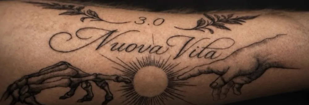 Schriftzug Nuova Vita mit Händen und Sonne am Unterarm